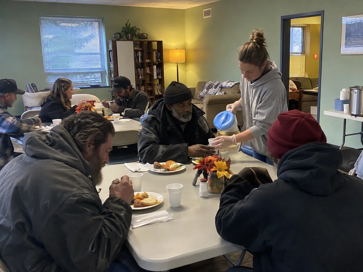 A volunteer serving drinks during a community meal.