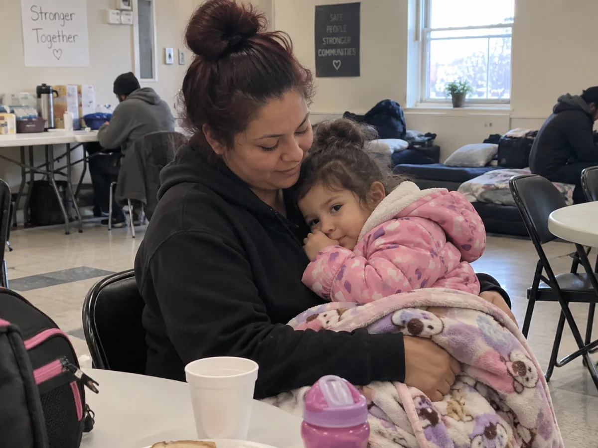 A mother holding a young child inside the winter shelter.